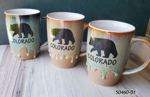 50460-01 Colorado Souvenir mug, 14 oz, approximately.  Each mug has a rough base and then a heavy drip reactive glaze in assorted tones.  Per pack of four, there will be two blue, one brown and one green toned mug.  All come with a black bear silhouette design that says Colorado. 